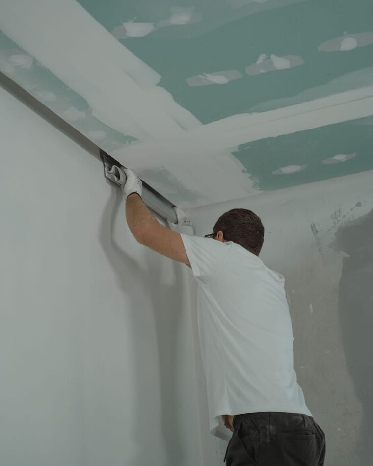 Trockenbauer verschraubt Gipskartonplatten an Decke und Wand