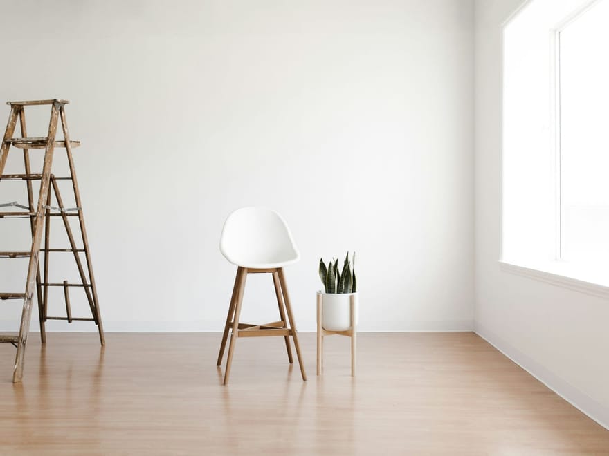 Frisch renovierter, leerer Raum mit Leiter und Stuhl
