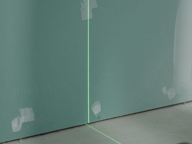 Kreuzlinienlaser projiziert eine Linie auf eine Trockenbauwand