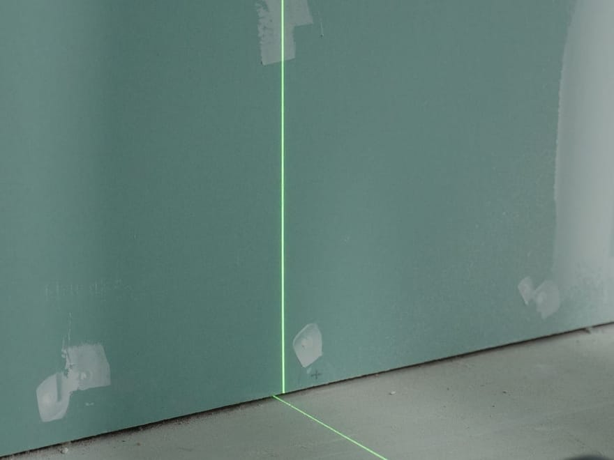 Kreuzlinienlaser projiziert eine Linie auf eine Trockenbauwand